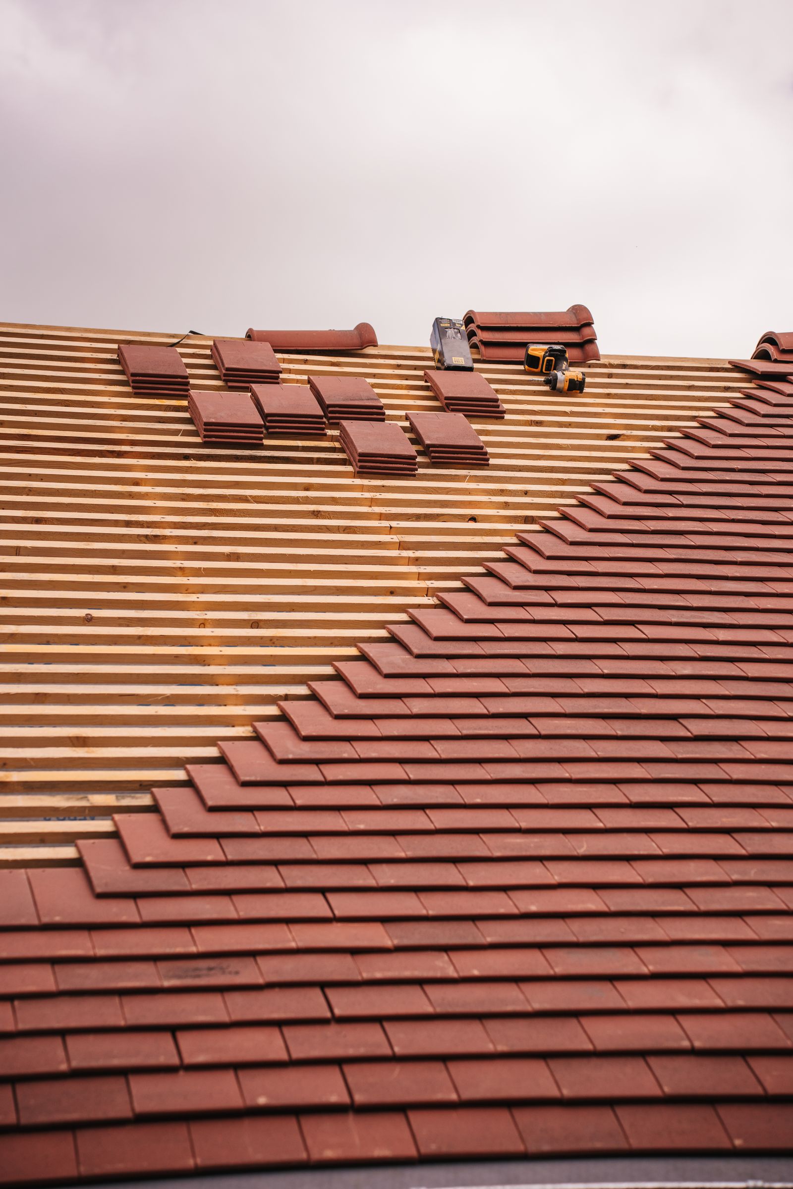 A roof mid-installation with new tiles being laid across the battens