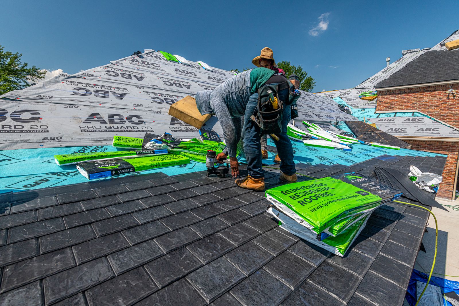 A roofer installing asphalt shingles on a residential roof